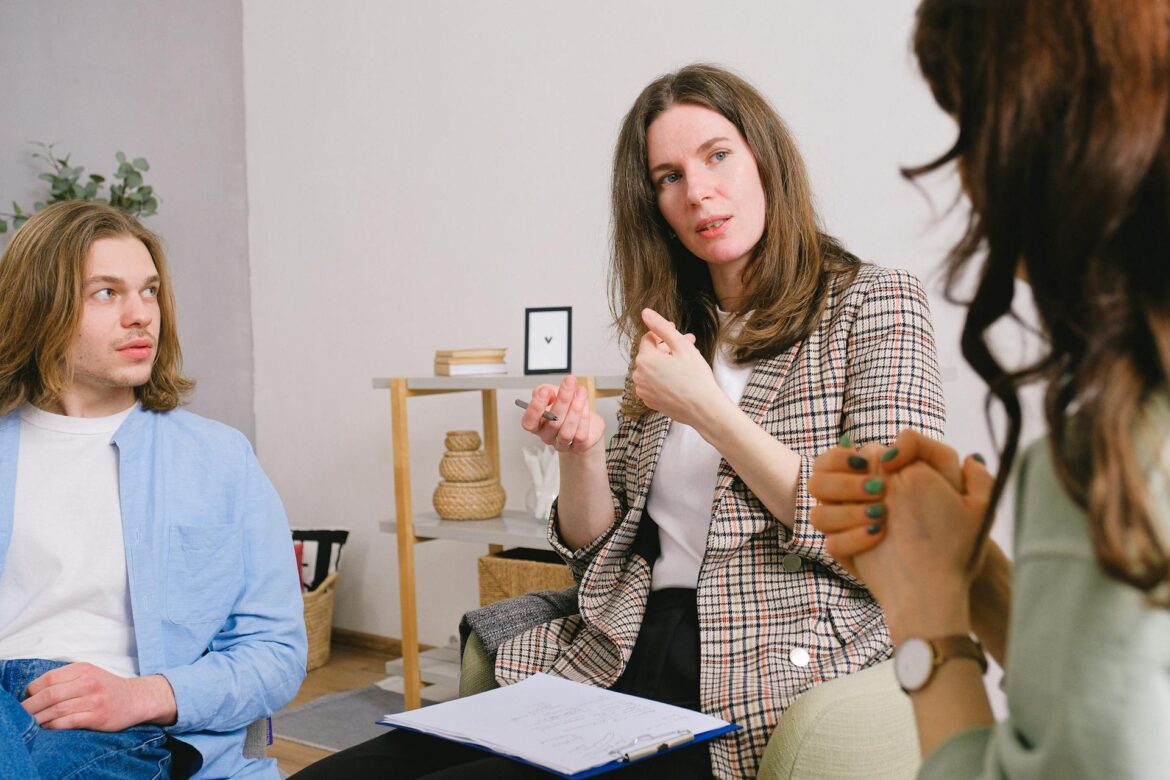 An image of a couple engaging in a candid conversation with a therapist, reflecting the process of addressing jealousy and insecurities in counseling.